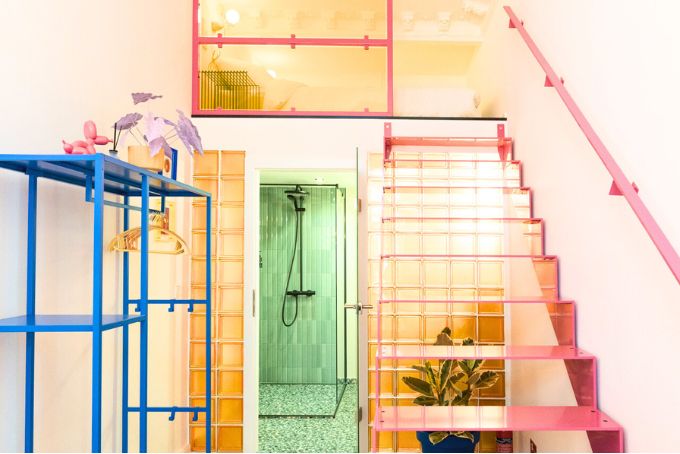 Bunte Treppe mit transparenten Stufen und einem modernen Badezimmer im Hintergrund, ideal für Wohnraumgestaltung.