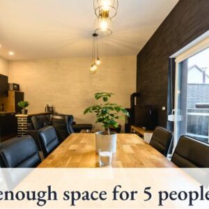 HelpMyBnB_Portfolio_Deutschland_Schamützelsee_Berlin_DE Modernes Esszimmer mit einem großen Tisch, der Platz für fünf Personen bietet, umgeben von schwarzen Stühlen und einer Pflanze.