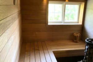 Innenansicht einer Sauna mit Holzverkleidung, einem Fenster und einer Sitzbank, ideal für Entspannung und Wellness.