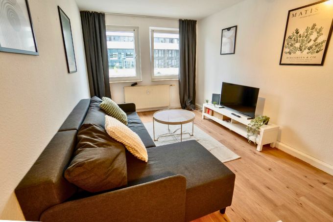 Ein modernes Wohnzimmer mit einem grauen Sofa, einem Couchtisch und einem Fernseher auf einem weißen TV-Ständer, ideal für Wohnideen.