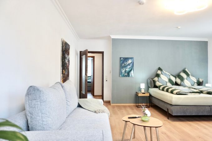 Blick im Wohnzimmer auf die Couch und das Kingsize Bett